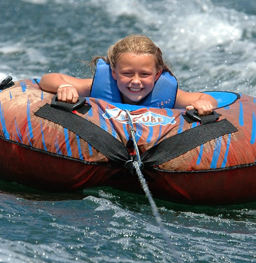 Young girl riding inner tube on water.