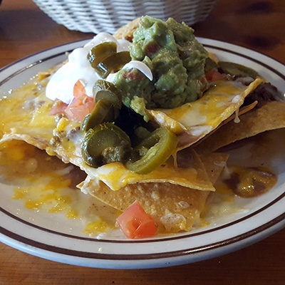Esther's nachos plate with chips, melted cheese, refried beans, jalapenos, guacamole, and sour cream.
