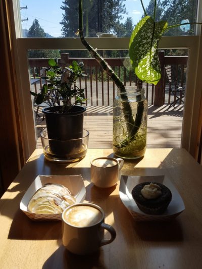 Sunshine through window lights table, coffee, and pastries.